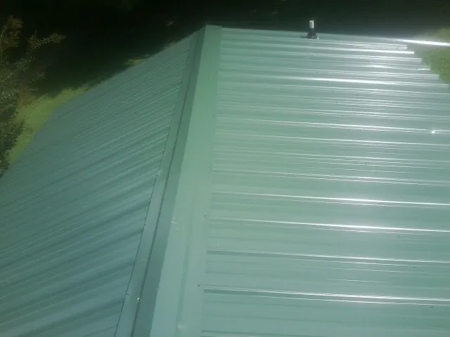 New green metal panels meeting at the ridge of a roof — Flat Roof Repair work by our crew in Williamson